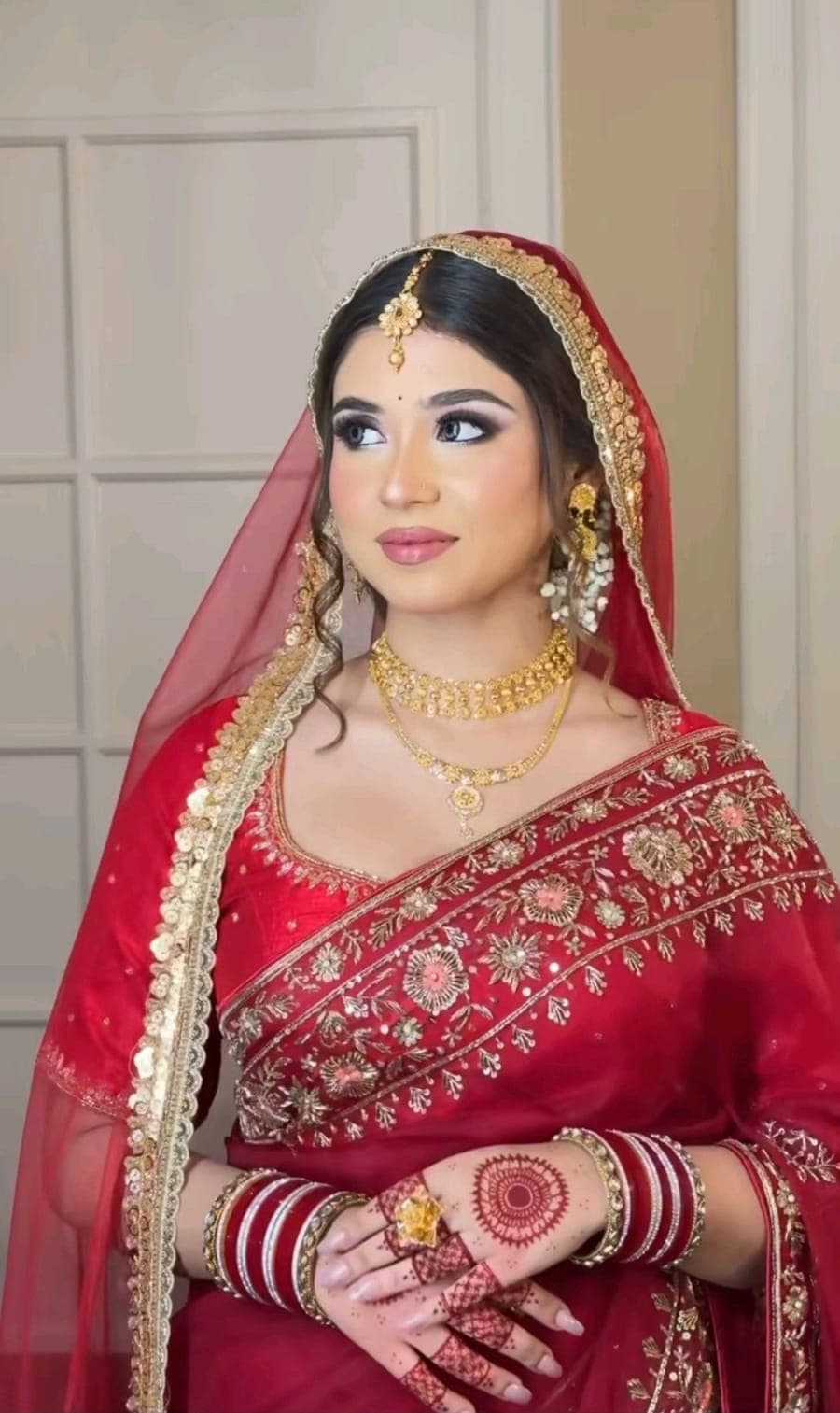Bride in a red saree and veil with traditional bridal jewellery